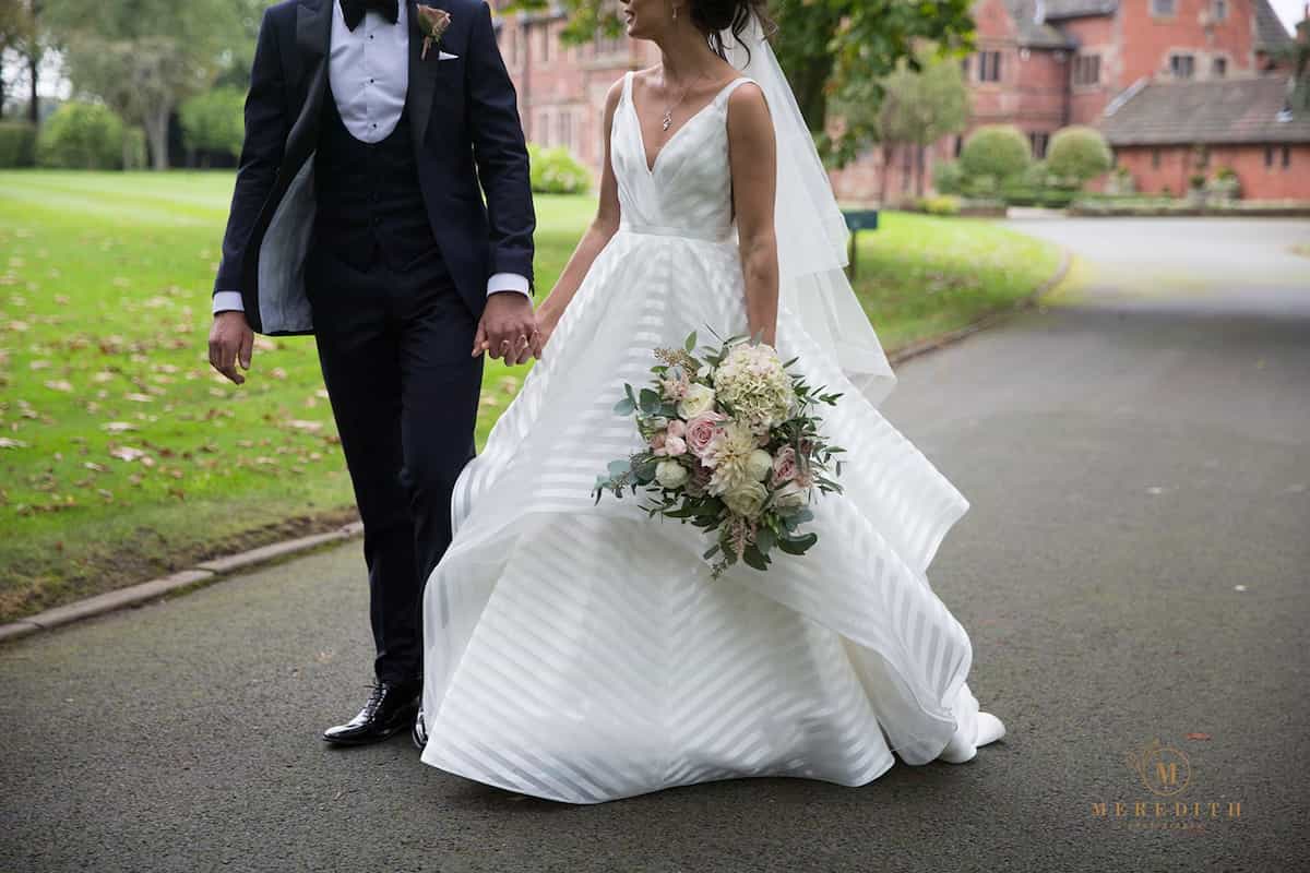 A bride and groom: the bride is holding a softly textured pale coloured bouquet