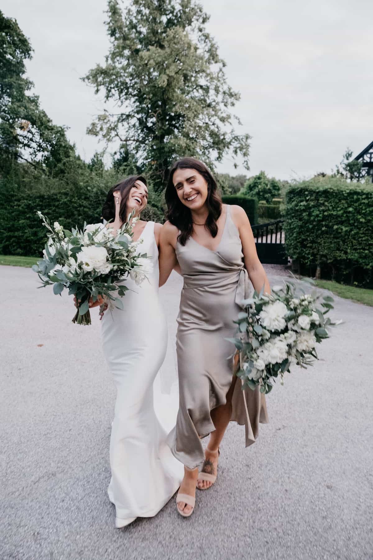 A bride and bridesmaid holding white bouquets