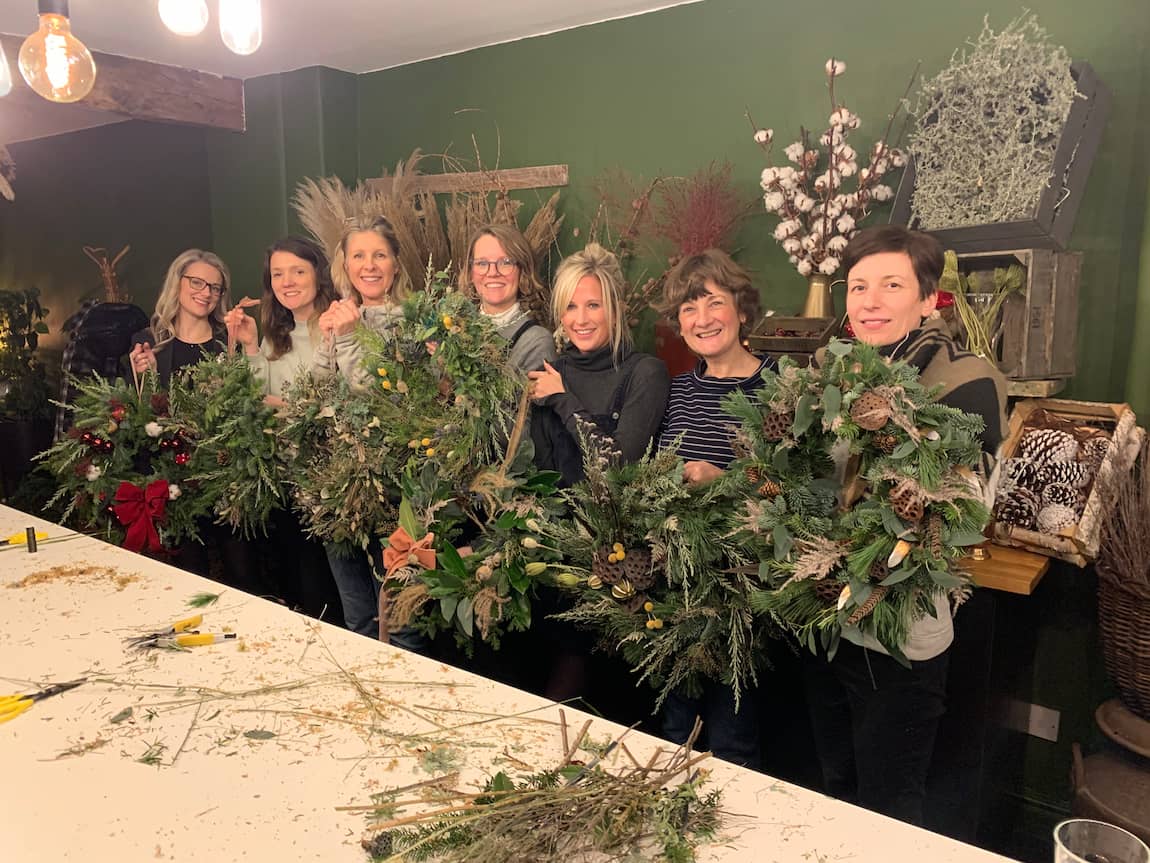 A group of workshop attendees show off their completed Christmas wreaths